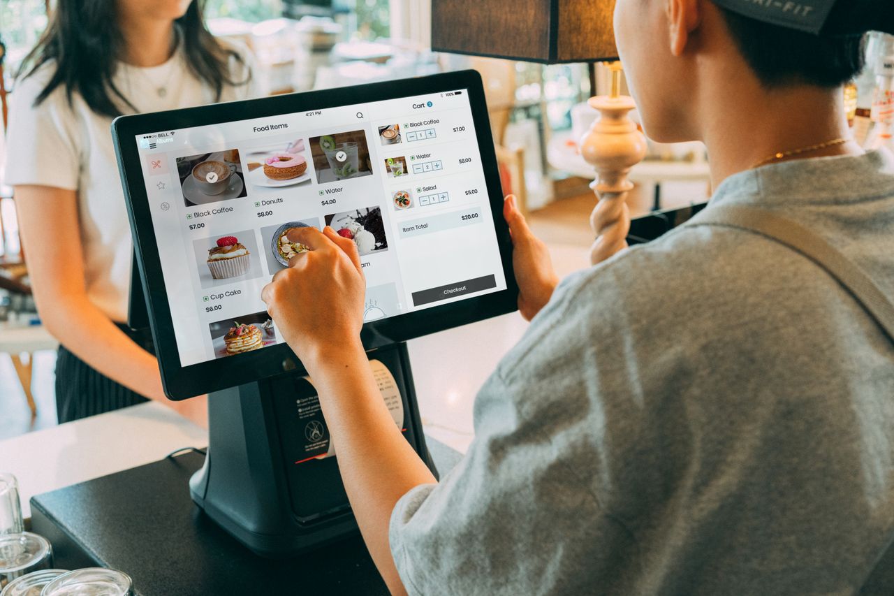 A customer using a touch screen system at a cafe counter for modern payment processing.