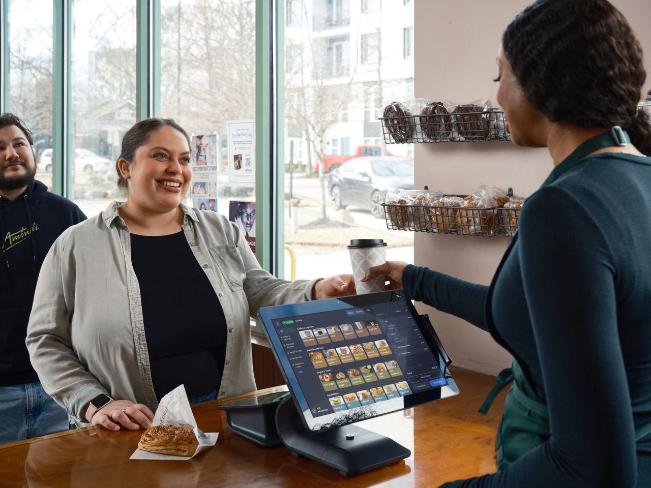 Crafting Captivating Headlines: Your awesome post title goes here Barista uses modern POS system in café; smiling customer with pastry and coffee in hand. Indoor café setting.