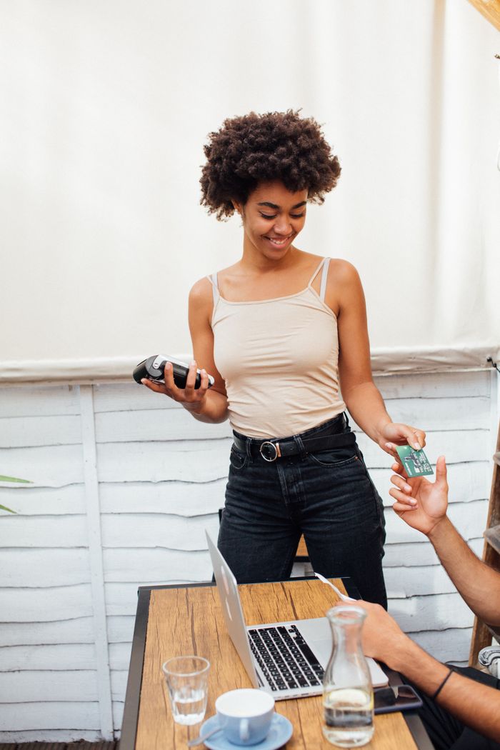 Woman smiling while handling payment transaction in a café setting.