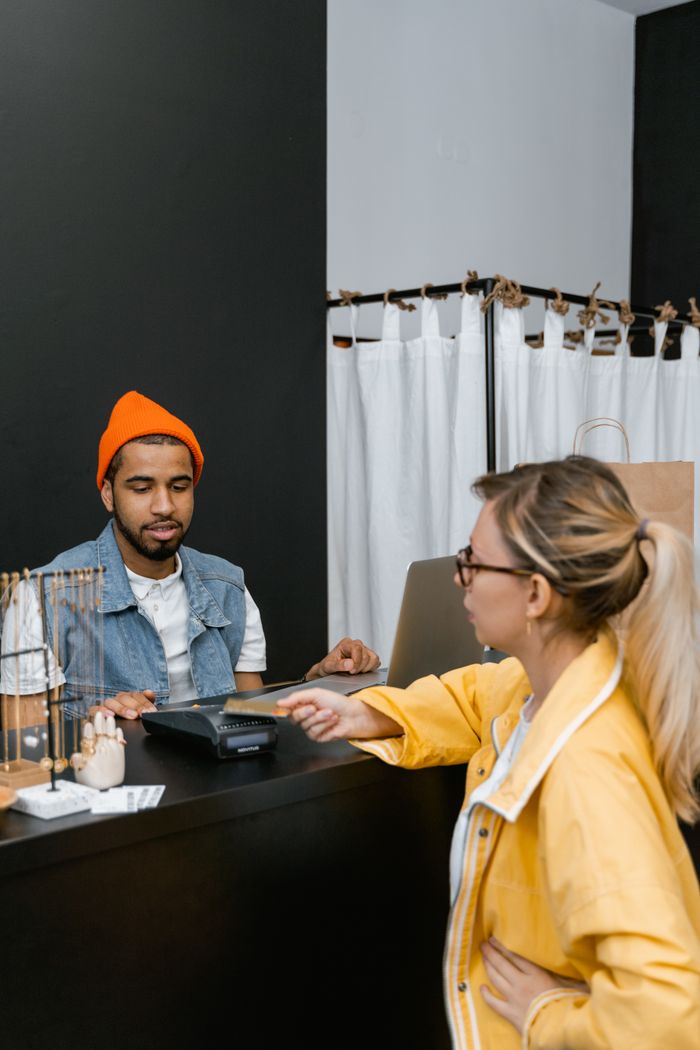 Customer using card for contactless payment at a fashion store counter with cashier.
